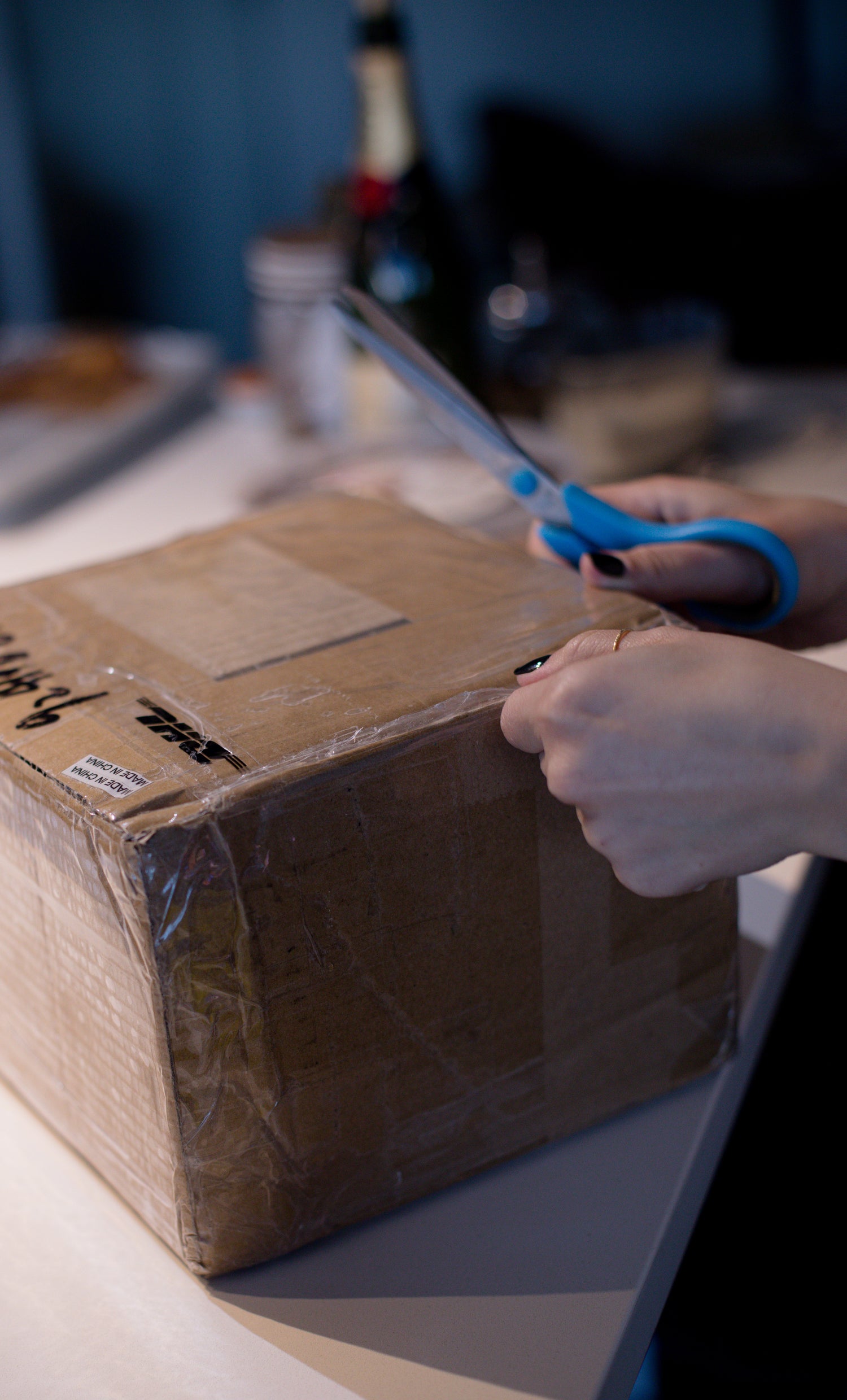 TAPED UP CARDBOARD BOX WITH A PERSON HOLDING SCISSORS